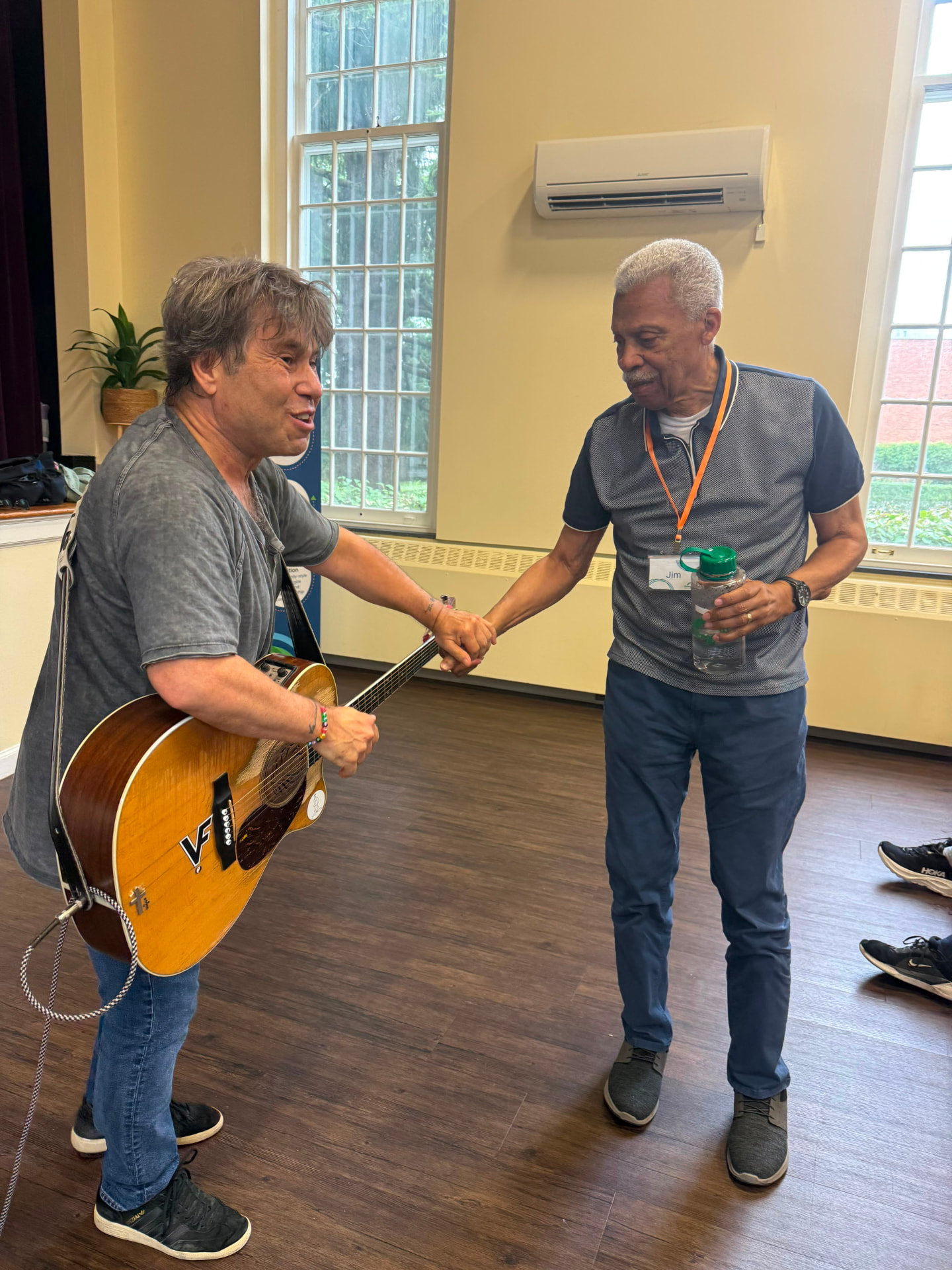 A guitarist shaking hands with an Evergreen member after a live music session