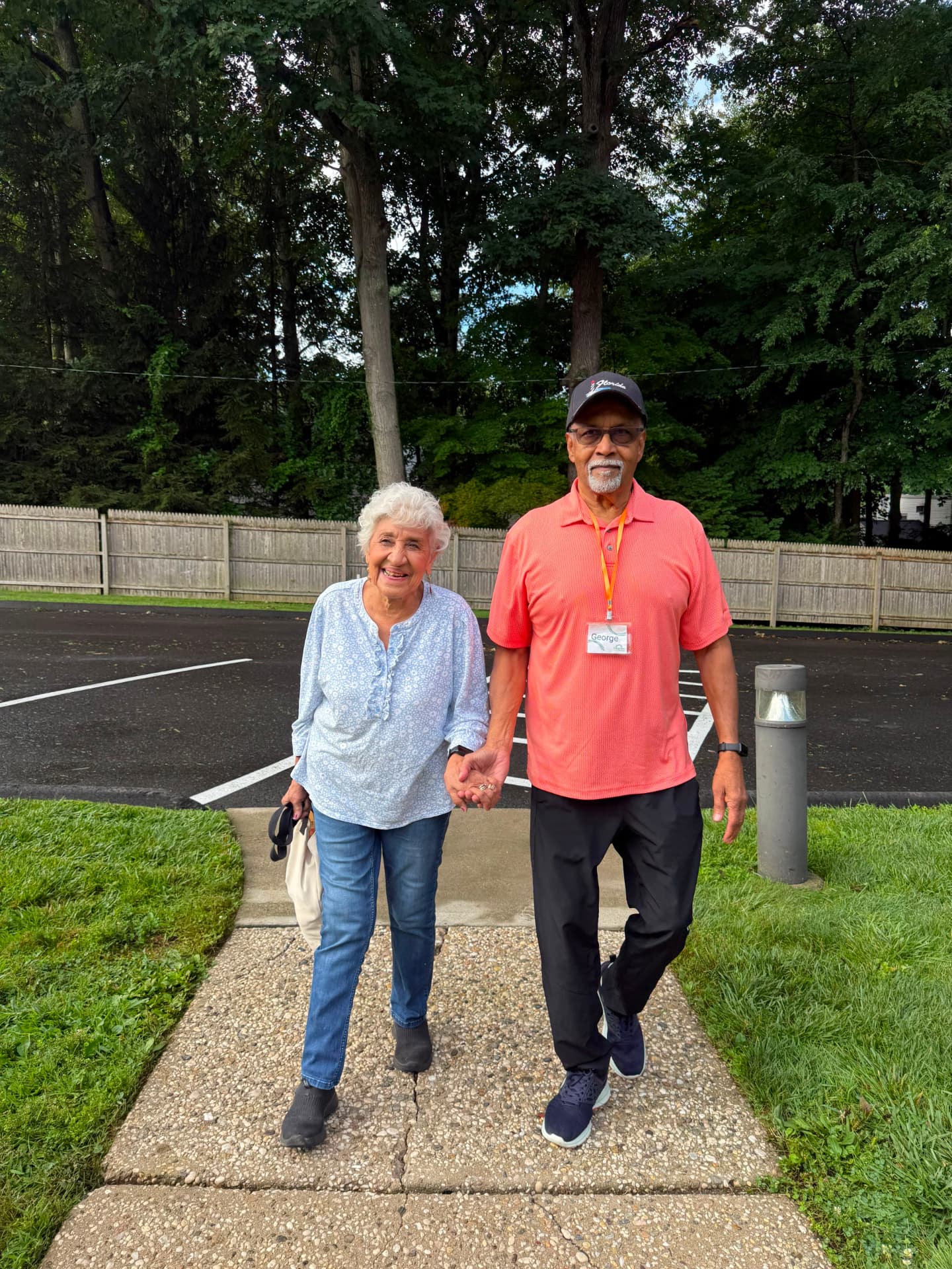 Two Evergreen members walking hand in hand along the path outside