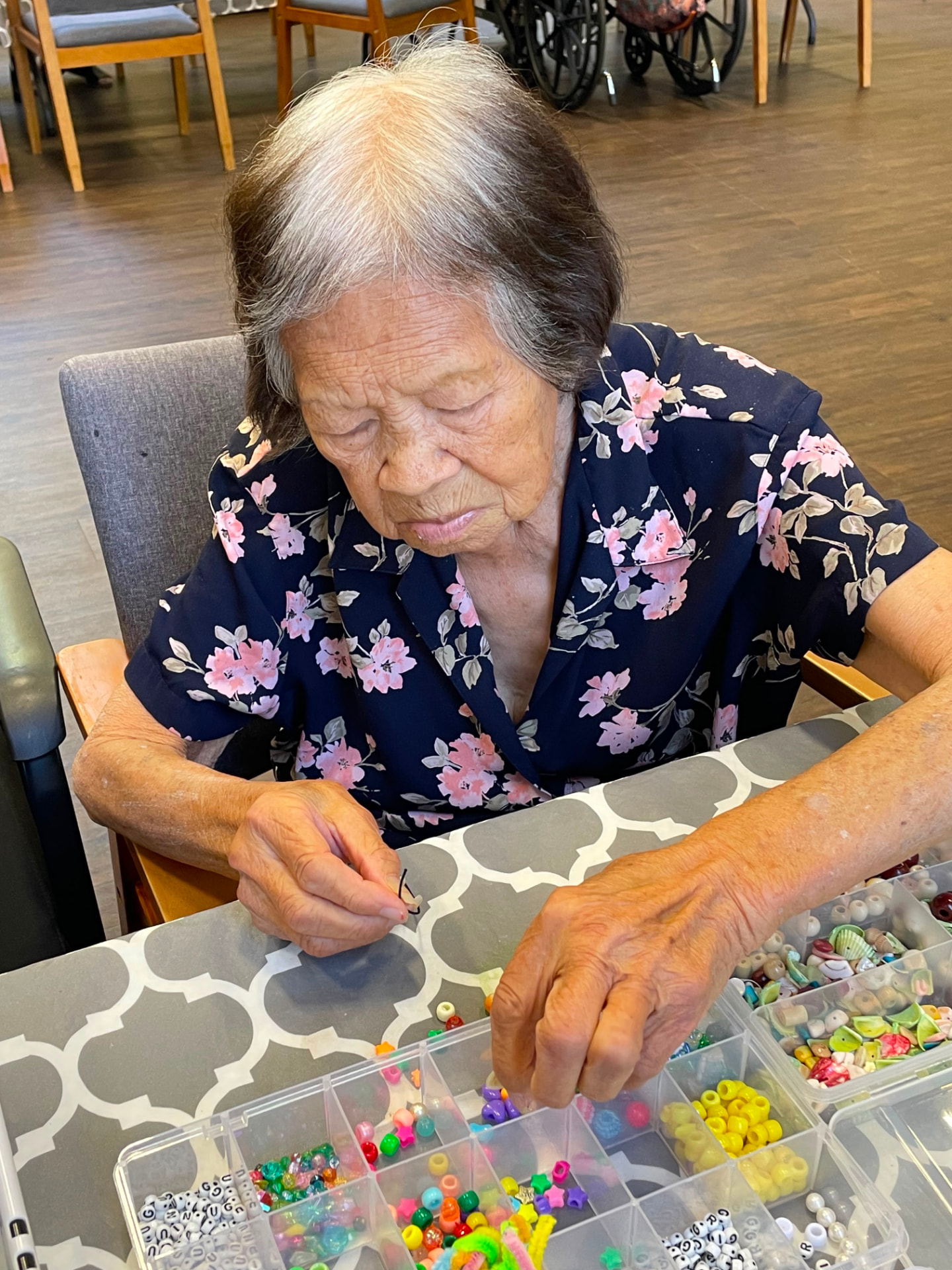 An Evergreen member threading colorful beads at the craft table