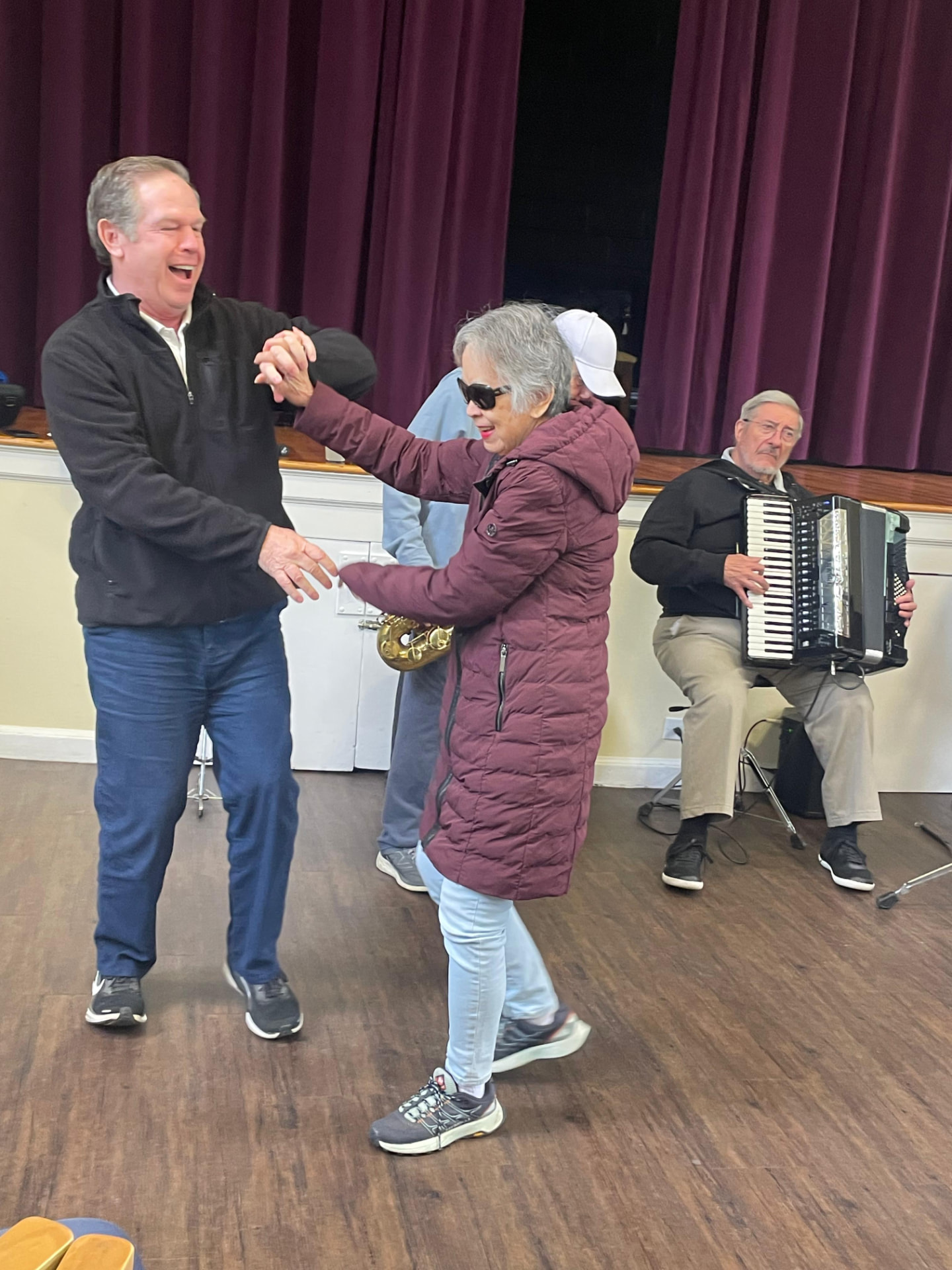 An Evergreen member dancing hand in hand with a staff member while a musician plays