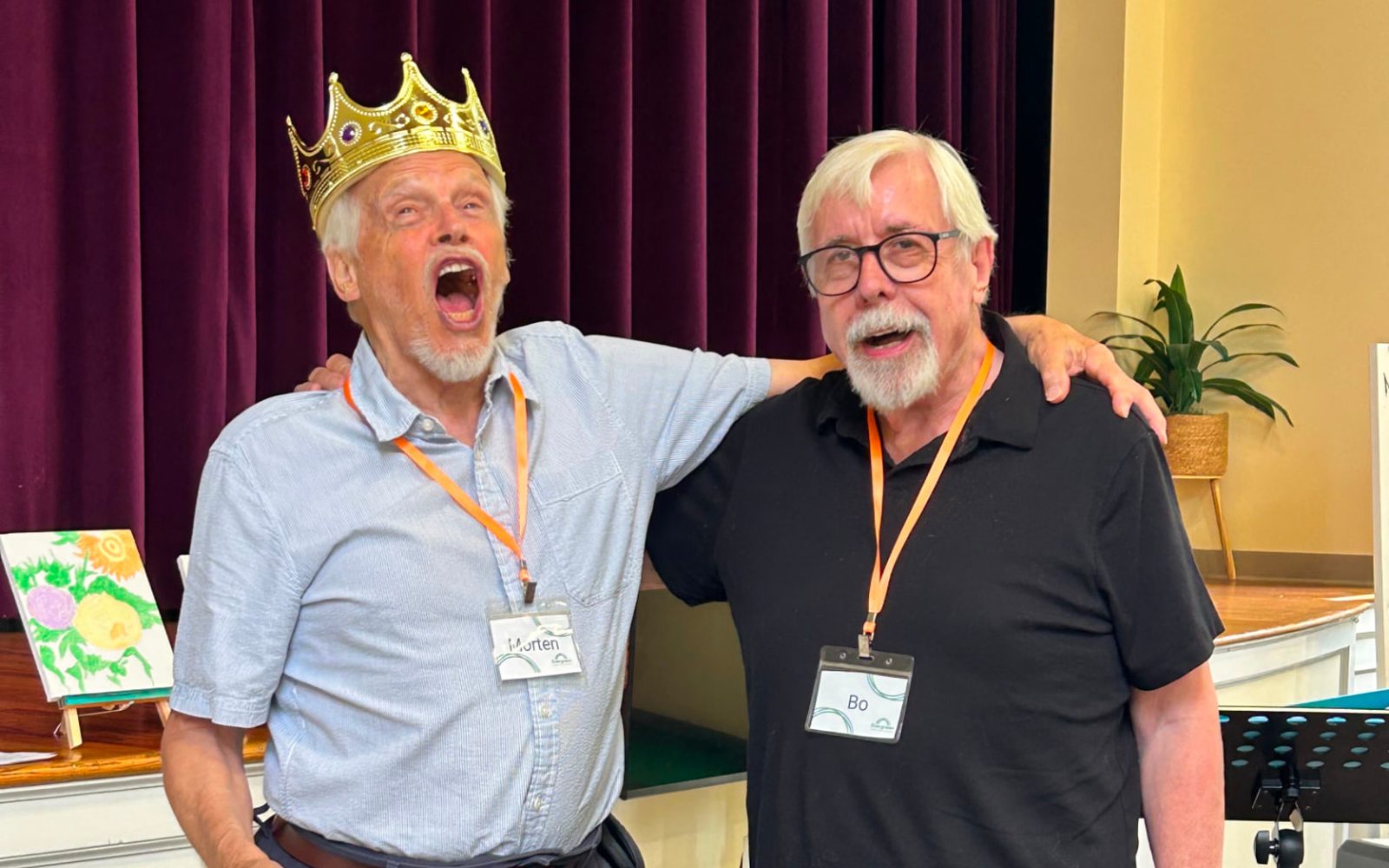 Two Evergreen members singing together, one wearing a gold crown